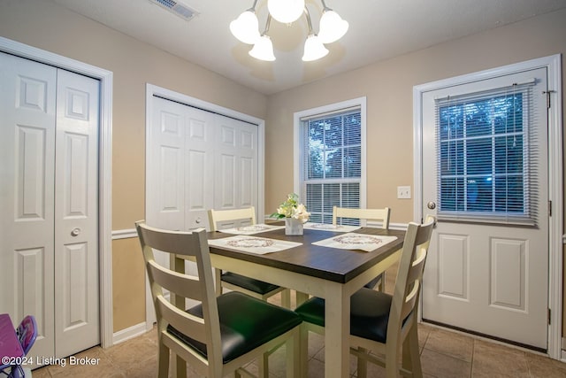 tiled dining area with a healthy amount of sunlight and a chandelier