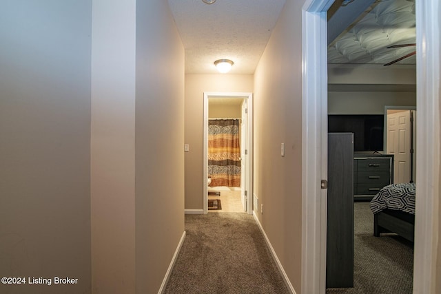 corridor featuring a textured ceiling and carpet floors