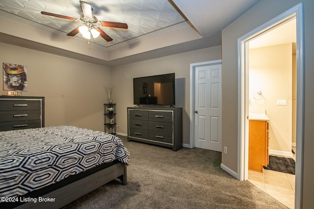 bedroom featuring connected bathroom, light colored carpet, ceiling fan, and a raised ceiling