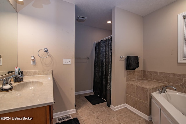 bathroom featuring tile patterned flooring, vanity, a textured ceiling, and a tub