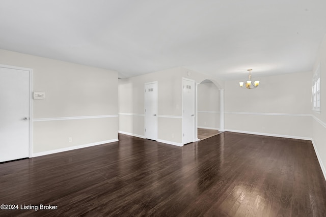 unfurnished room featuring a notable chandelier and dark hardwood / wood-style floors