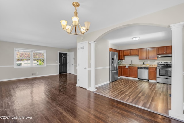 kitchen featuring stainless steel appliances, decorative columns, a notable chandelier, pendant lighting, and dark hardwood / wood-style flooring