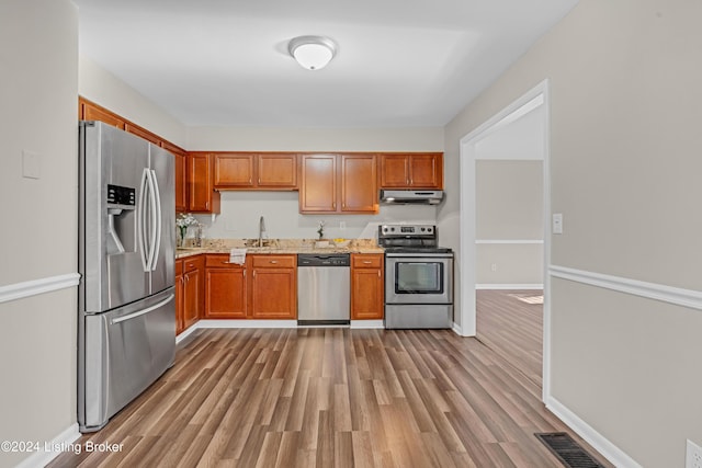 kitchen with sink, stainless steel appliances, and light hardwood / wood-style flooring