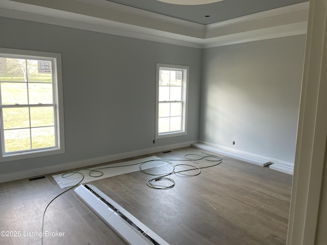 spare room with crown molding, light wood-type flooring, and a wealth of natural light