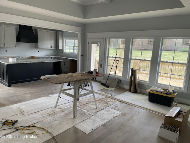 kitchen with custom range hood, gray cabinetry, and light hardwood / wood-style floors