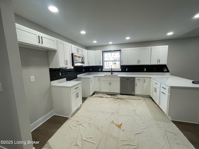 kitchen with tasteful backsplash, white cabinets, appliances with stainless steel finishes, light countertops, and a sink