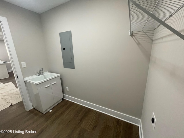 laundry area featuring hookup for an electric dryer, dark wood-type flooring, a sink, baseboards, and electric panel