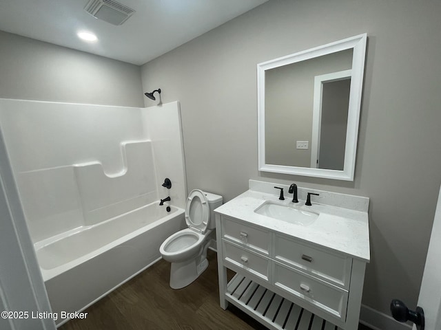 bathroom with bathtub / shower combination, toilet, wood finished floors, vanity, and visible vents