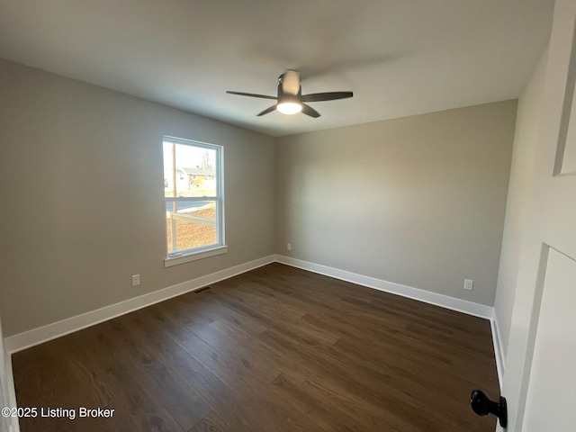 empty room featuring a ceiling fan, visible vents, dark wood finished floors, and baseboards