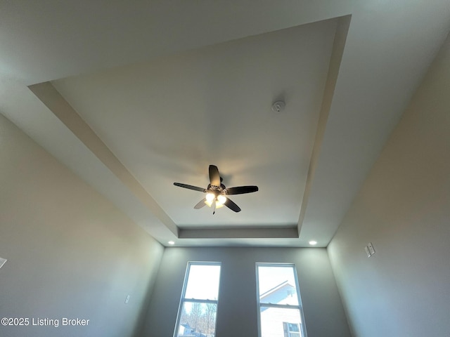 details with a tray ceiling and a ceiling fan