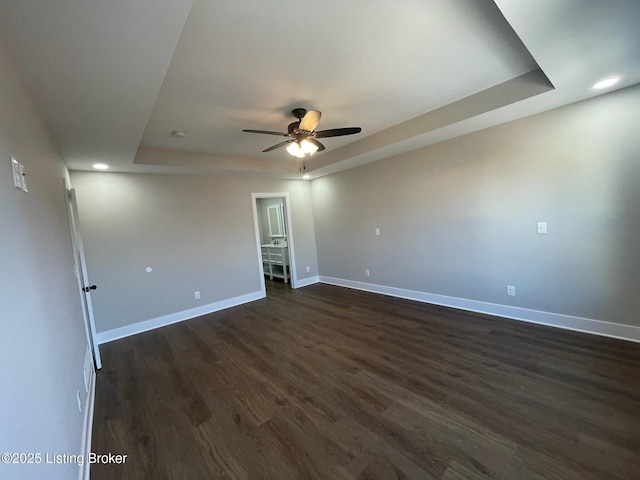 unfurnished room with baseboards, a raised ceiling, a ceiling fan, dark wood-style floors, and recessed lighting