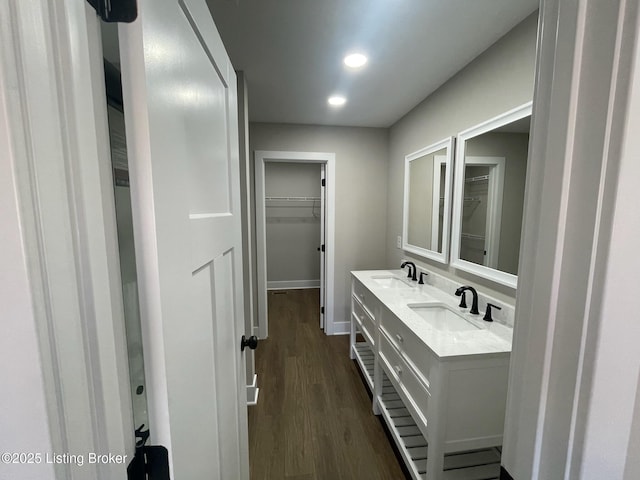 full bathroom with double vanity, baseboards, a sink, and wood finished floors