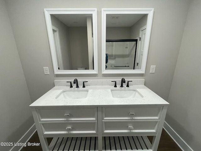 bathroom with double vanity, baseboards, and a sink