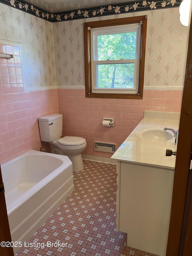 bathroom with tile patterned floors, vanity, a tub to relax in, and tile walls