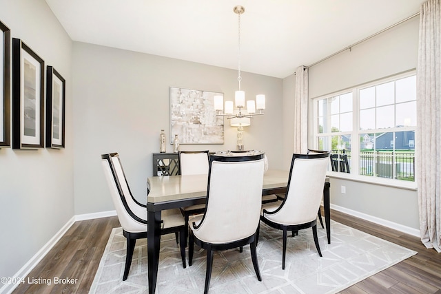 dining space featuring wood-type flooring and a notable chandelier