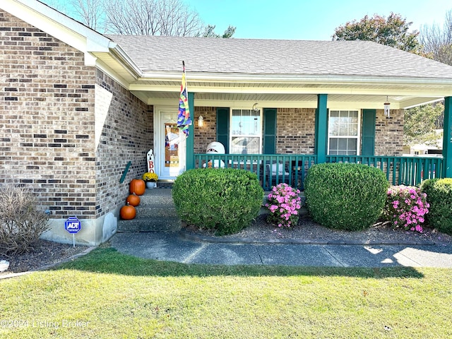 doorway to property featuring covered porch and a yard