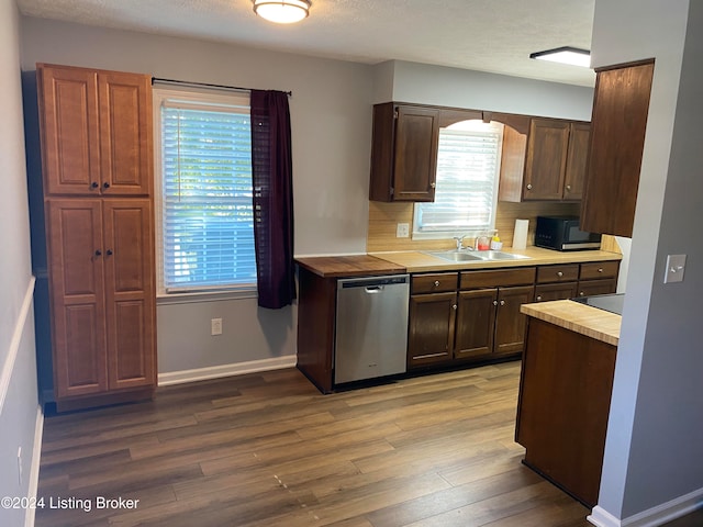 kitchen featuring stainless steel dishwasher, sink, hardwood / wood-style flooring, and a textured ceiling