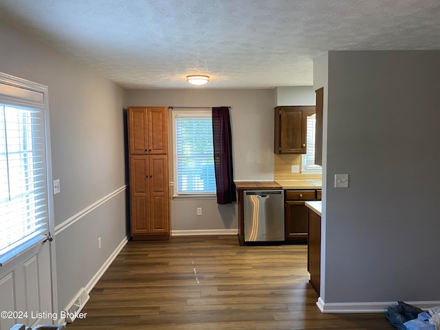 kitchen featuring a healthy amount of sunlight, a textured ceiling, stainless steel dishwasher, and dark hardwood / wood-style floors