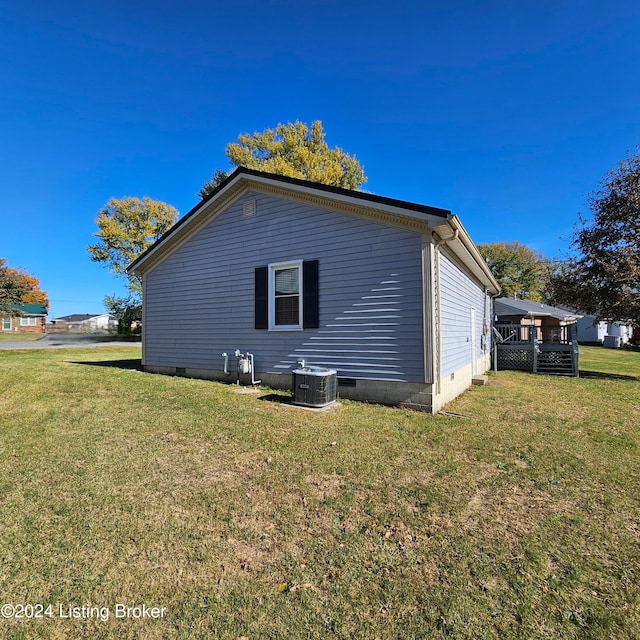 view of side of home with central AC and a lawn