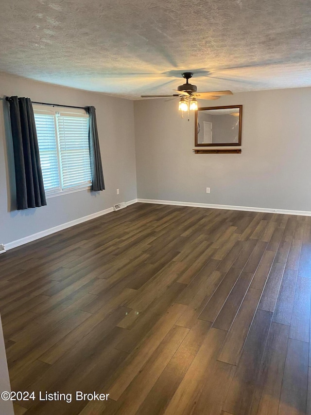 empty room with a textured ceiling, dark wood-type flooring, and ceiling fan