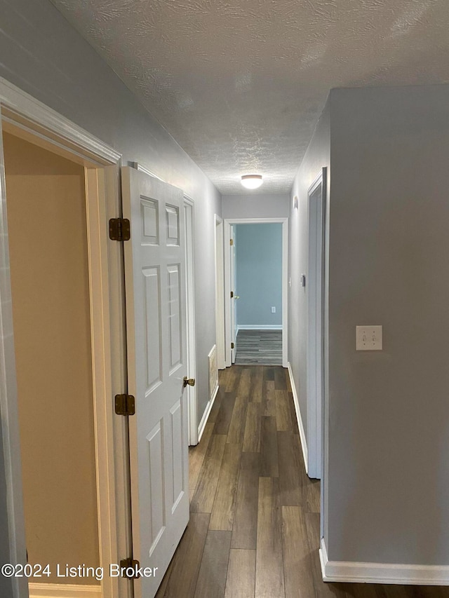 hall featuring a textured ceiling and dark hardwood / wood-style flooring