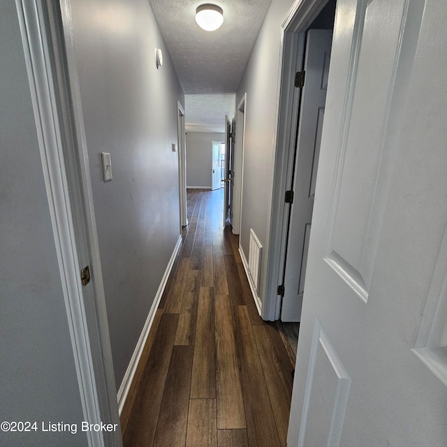 corridor featuring a textured ceiling and dark hardwood / wood-style flooring