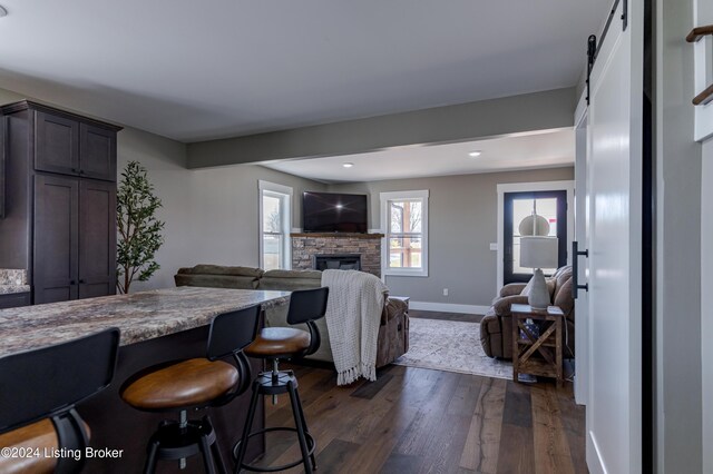 216 Millerstown St, Clarkson, KY 42726 - kitchen with a stone fireplace, dark wood-type flooring, baseboards, a barn door, and open floor plan