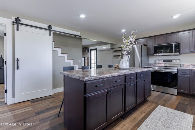 216 Millerstown St, Clarkson, KY 42726 - kitchen featuring stainless steel appliances, a barn door, dark wood finished floors, a kitchen island, and light stone counters
