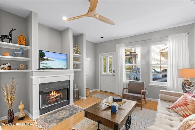 living room with light hardwood / wood-style floors, a tile fireplace, and built in shelves