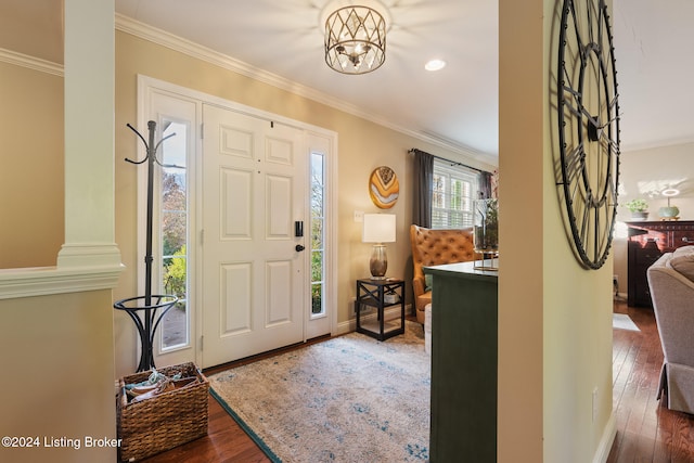 entrance foyer featuring ornamental molding, dark wood-type flooring, and an inviting chandelier