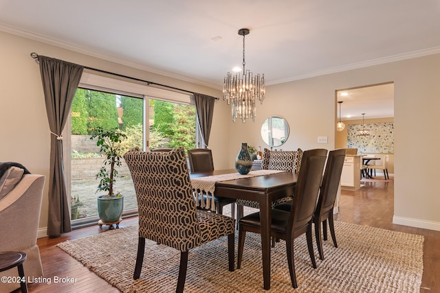 dining area with hardwood / wood-style floors, crown molding, and a notable chandelier