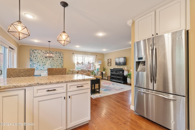 kitchen with stainless steel fridge, a healthy amount of sunlight, light wood-type flooring, and white cabinetry