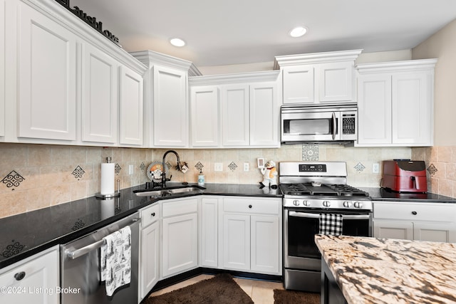 kitchen featuring white cabinets, dark stone counters, sink, and appliances with stainless steel finishes