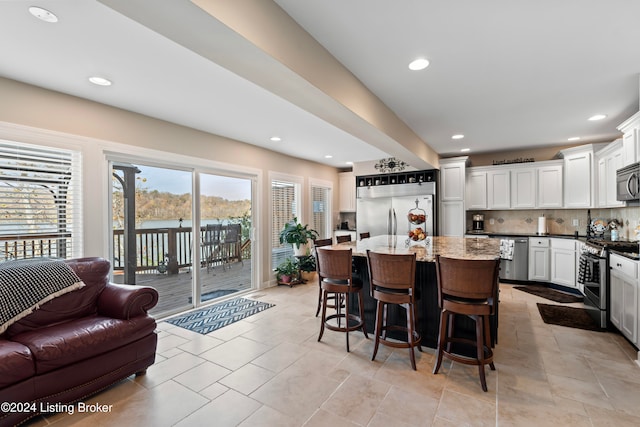 kitchen featuring tasteful backsplash, appliances with stainless steel finishes, light stone countertops, white cabinets, and a center island