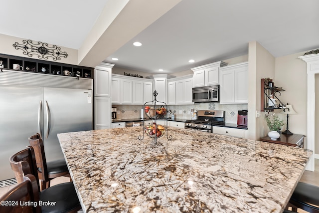 kitchen with light stone countertops, appliances with stainless steel finishes, and a breakfast bar area