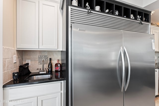 kitchen featuring white cabinetry, stainless steel built in refrigerator, sink, and tasteful backsplash