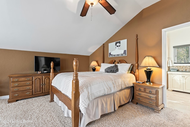 carpeted bedroom with ensuite bathroom, ceiling fan, and vaulted ceiling