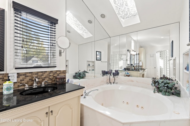 bathroom featuring lofted ceiling with skylight, vanity, and a bathing tub