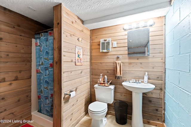 bathroom featuring toilet, wood walls, a textured ceiling, sink, and a shower with shower curtain