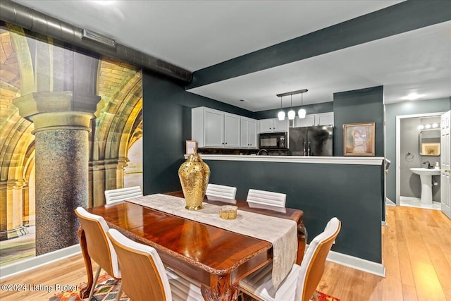 dining area featuring sink, ornate columns, and light hardwood / wood-style flooring