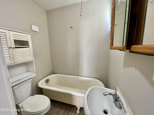 bathroom with toilet, a tub to relax in, and wood-type flooring