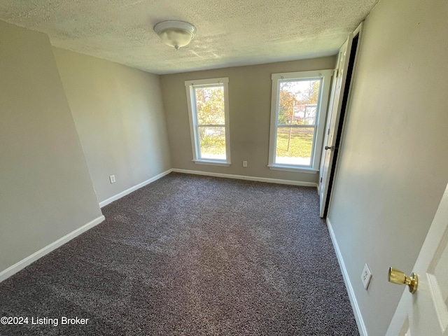 carpeted empty room featuring a textured ceiling