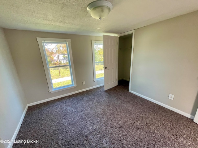 carpeted empty room with a textured ceiling