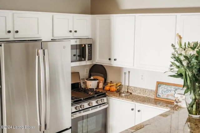 kitchen with light stone countertops, white cabinets, and stainless steel appliances