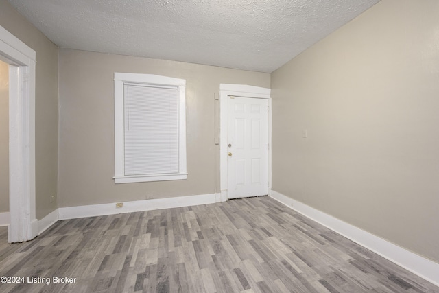 unfurnished room with a textured ceiling and light wood-type flooring