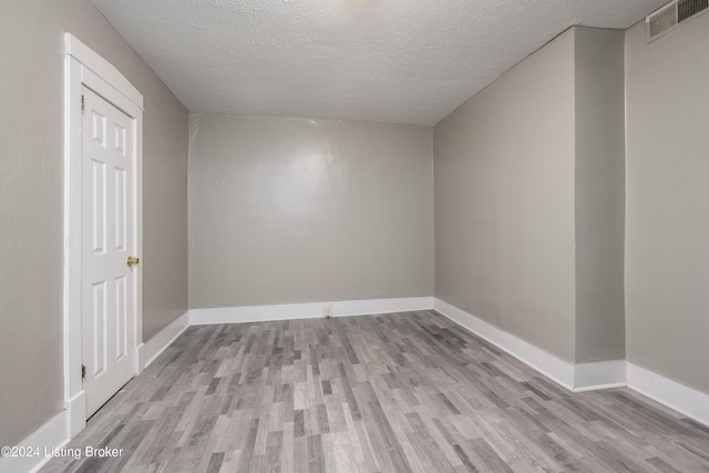 unfurnished room featuring light hardwood / wood-style flooring and a textured ceiling