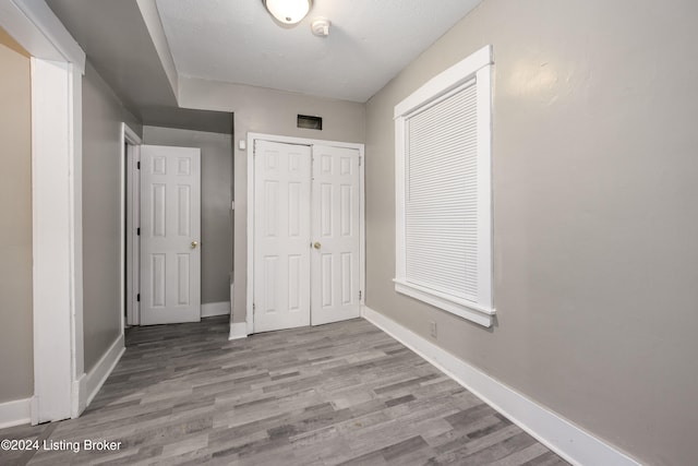 unfurnished bedroom featuring light hardwood / wood-style flooring, a textured ceiling, and a closet