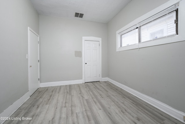 unfurnished room featuring light wood-type flooring and a textured ceiling