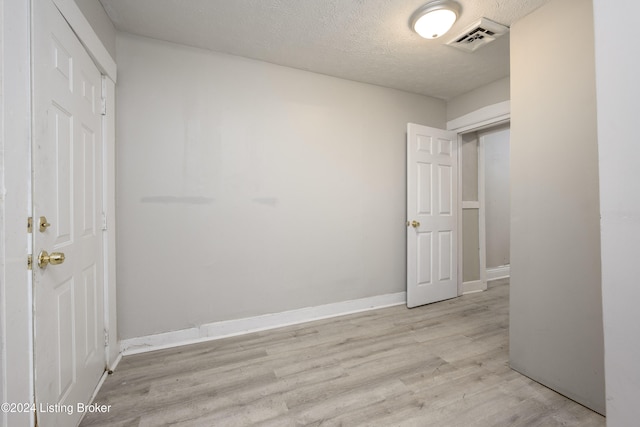 unfurnished bedroom featuring light hardwood / wood-style floors, a textured ceiling, and a closet