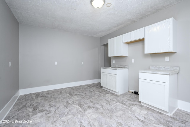 kitchen featuring white cabinetry and a textured ceiling